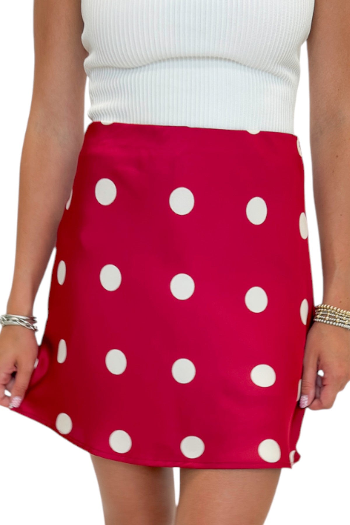 Front detail view of woman wearing Swagger Boutique’s white top with Red &amp; Cream Polka Dot Satin Mini Skirt against white studio background.