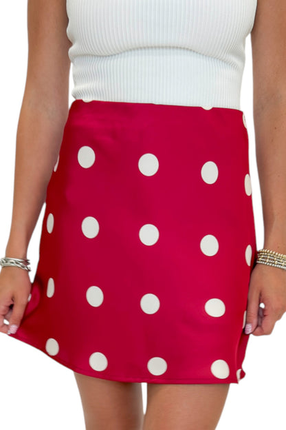 Front detail view of woman wearing Swagger Boutique’s white top with Red &amp; Cream Polka Dot Satin Mini Skirt against white studio background.