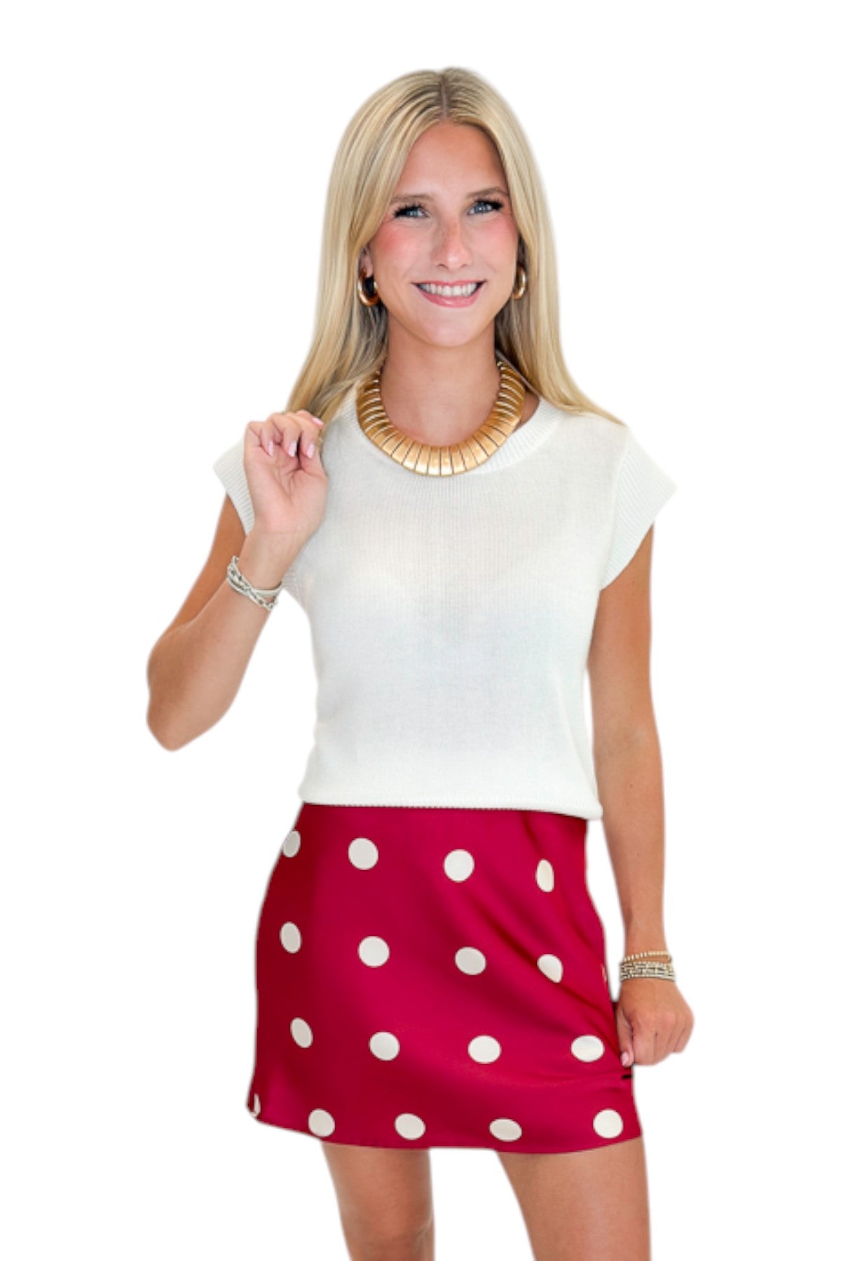 Front view of woman wearing Swagger Boutique’s white top with Red &amp; Cream Polka Dot Satin Mini Skirt against white studio background.