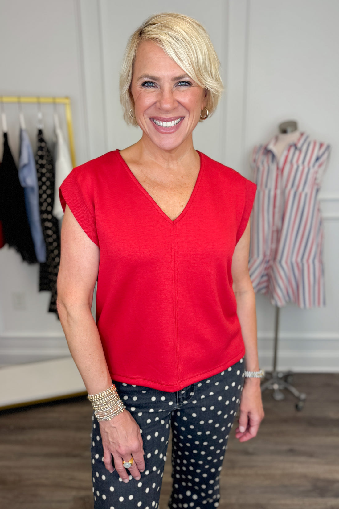 Front view of woman wearing Swagger Boutique’s Red V-Neck Tank by Entro with jeans against white studio background.