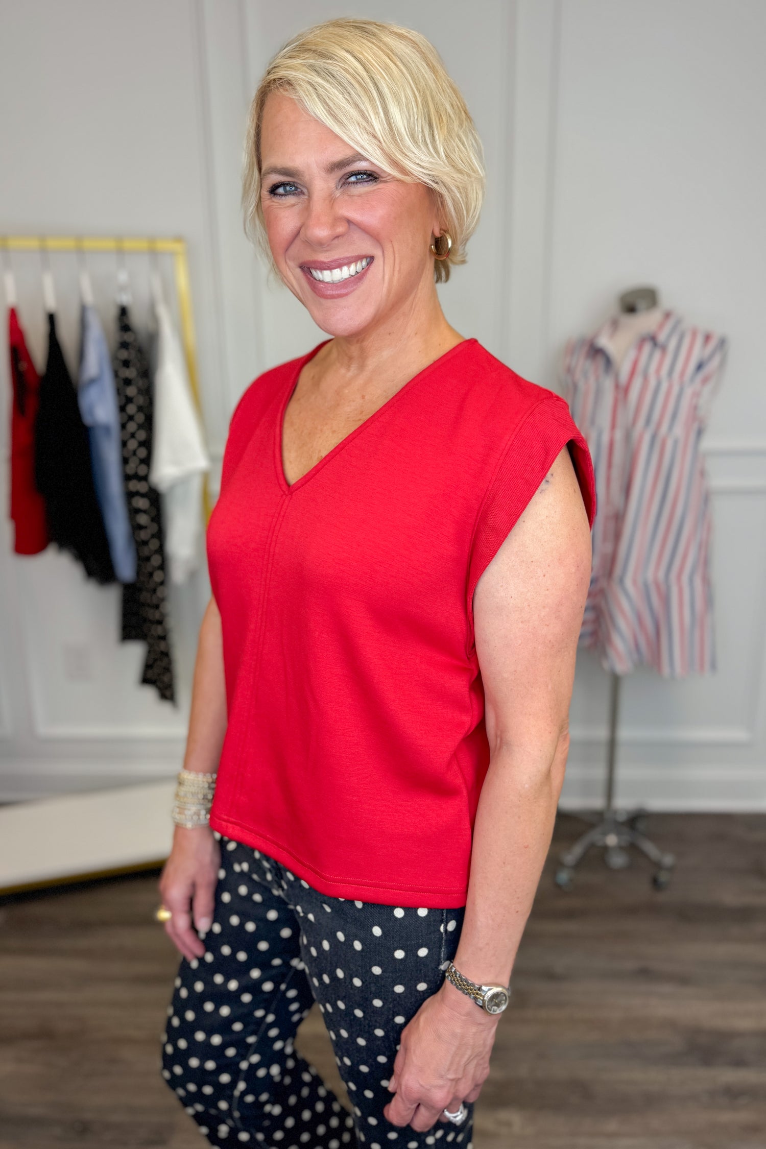 Side view of woman wearing Swagger Boutique’s Red V-Neck Tank by Entro with jeans against white studio background.