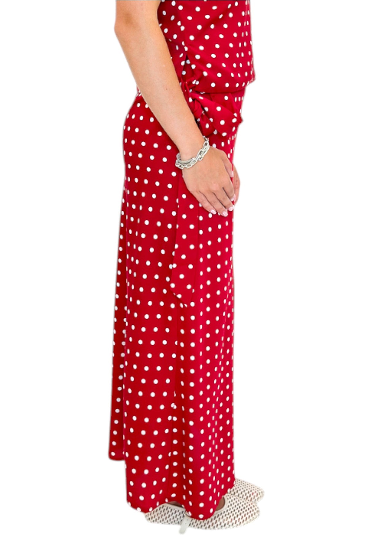 Side detail view of woman wearing Swagger Boutique’s Red &amp; White Polka Dot Midi Skirt with Red &amp; White Polka Dot Asymmetrical Tank against white studio background.