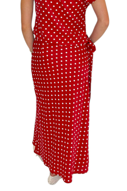 Back view of woman wearing Swagger Boutique’s Red &amp; White Polka Dot Midi Skirt with Red &amp; White Polka Dot Asymmetrical Tank against white studio background.