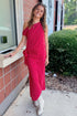 Front view of woman wearing Swagger Boutique’s Red & White Polka Dot Midi Skirt with Red & White Polka Dot Asymmetrical Tank standing outside a ticket office.