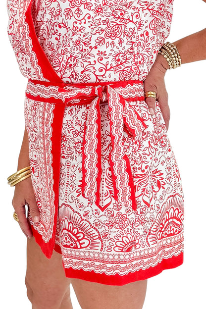 Side detail view of woman wearing Swagger Boutique’s Red &amp; White Printed Romper by Skies Are Blue with sandals against white studio background.