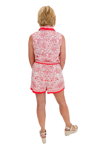 Back view of woman wearing Swagger Boutique’s Red &amp; White Printed Romper by Skies Are Blue with sandals against white studio background.