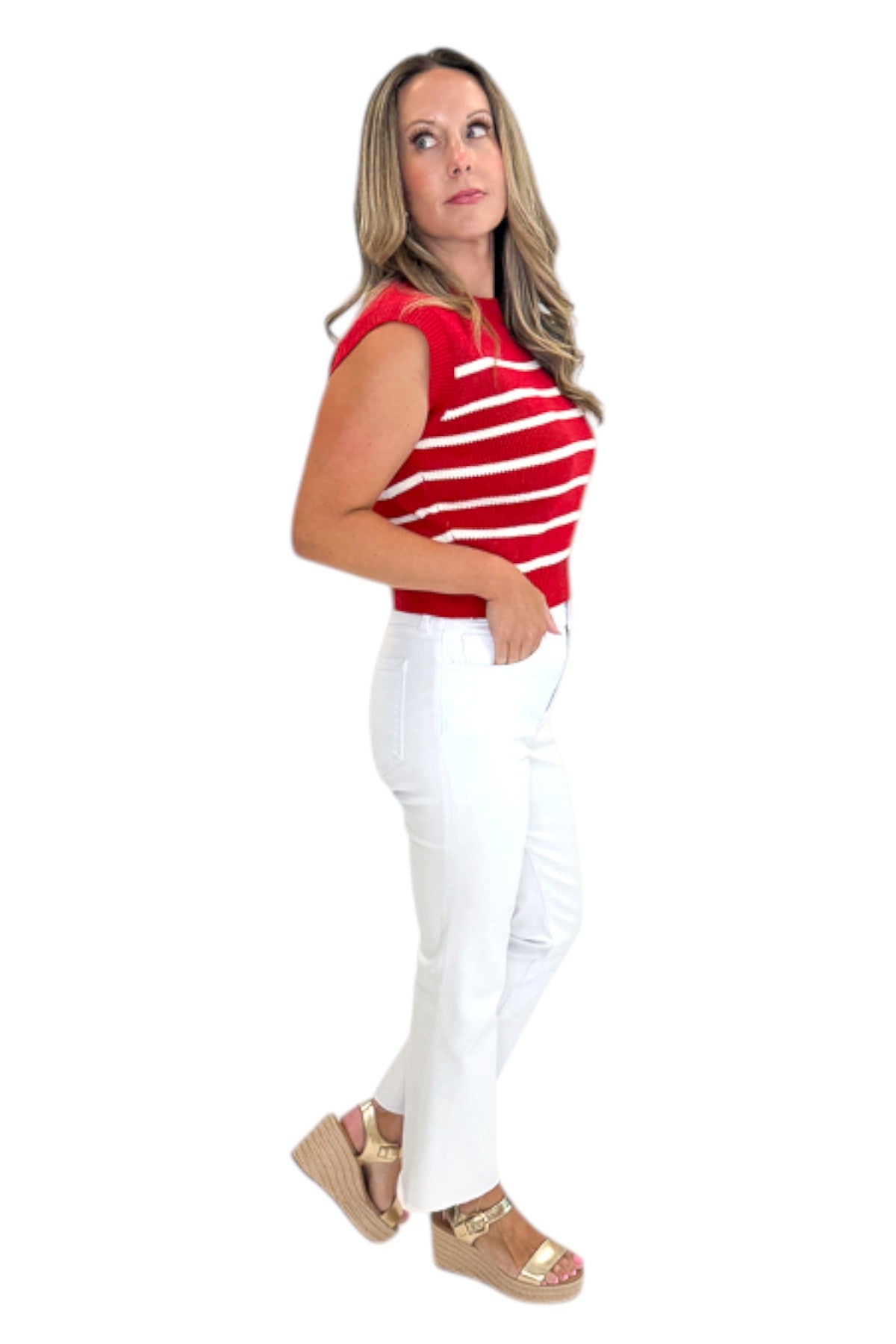 Side view of woman wearing Swagger Boutique’s Red &amp; White Striped Sleeveless Sweater with jeans against white studio background.