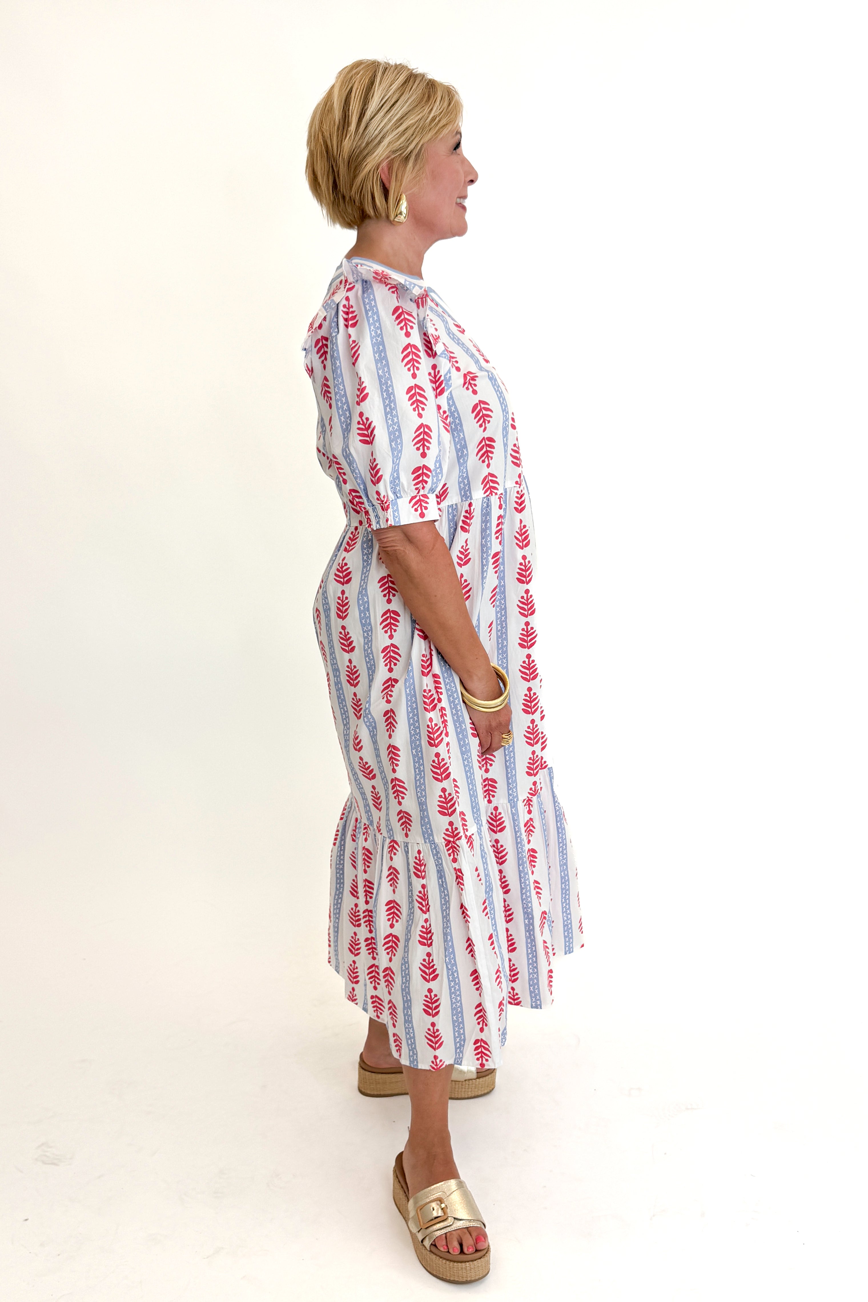 Side view of woman wearing Swagger Boutique’s Red, White &amp; Blue Jonah Midi Dress by MudPie with Lulah Platform Sandals against white studio background.