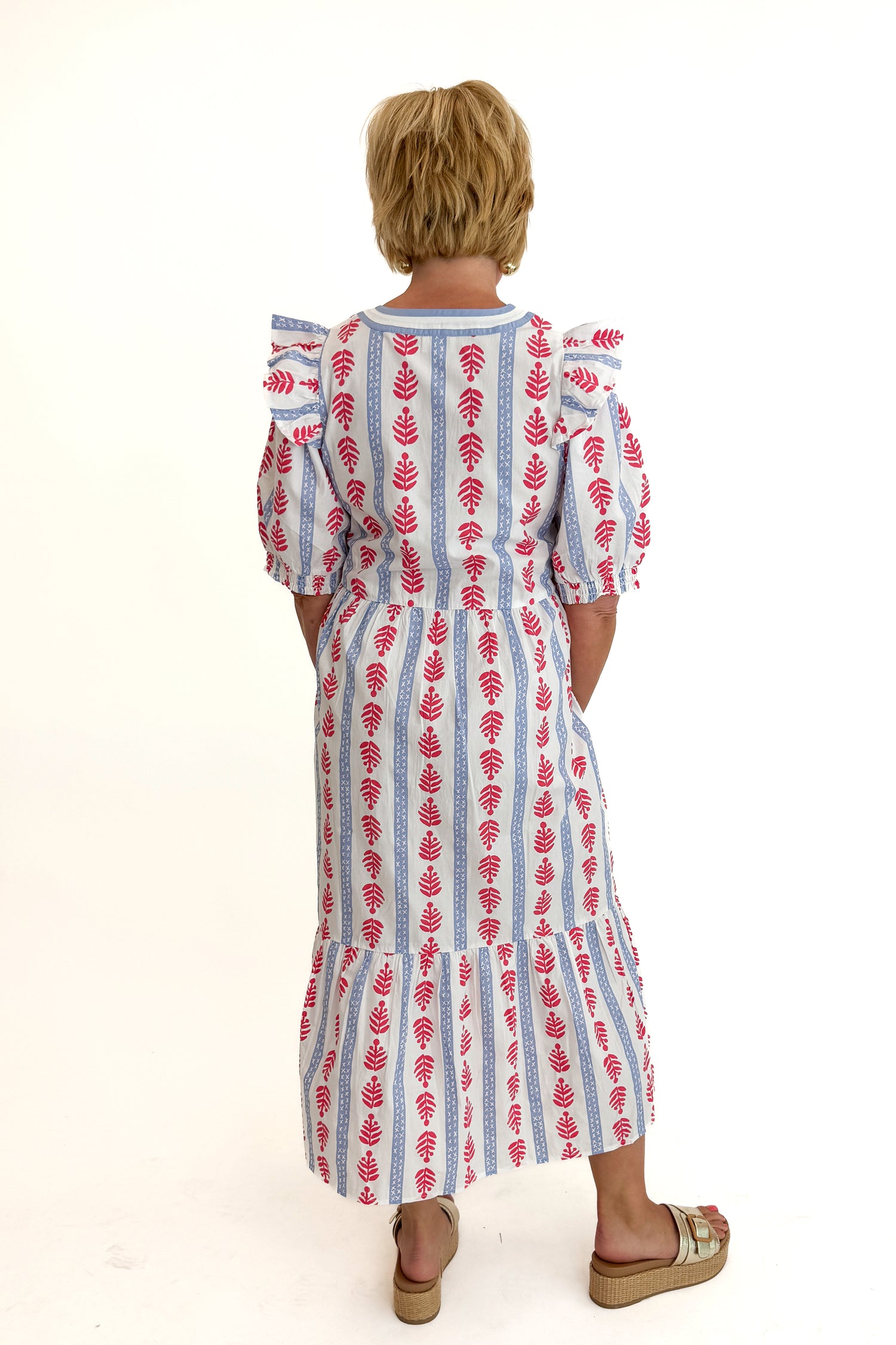 Back view of woman wearing Swagger Boutique’s Red, White &amp; Blue Jonah Midi Dress by MudPie with Lulah Platform Sandals against white studio background.