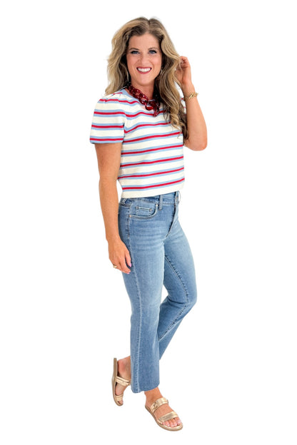 Side view of woman wearing Swagger Boutique’s Red, White &amp; Blue Striped Top by Entro with jeans against white studio background.