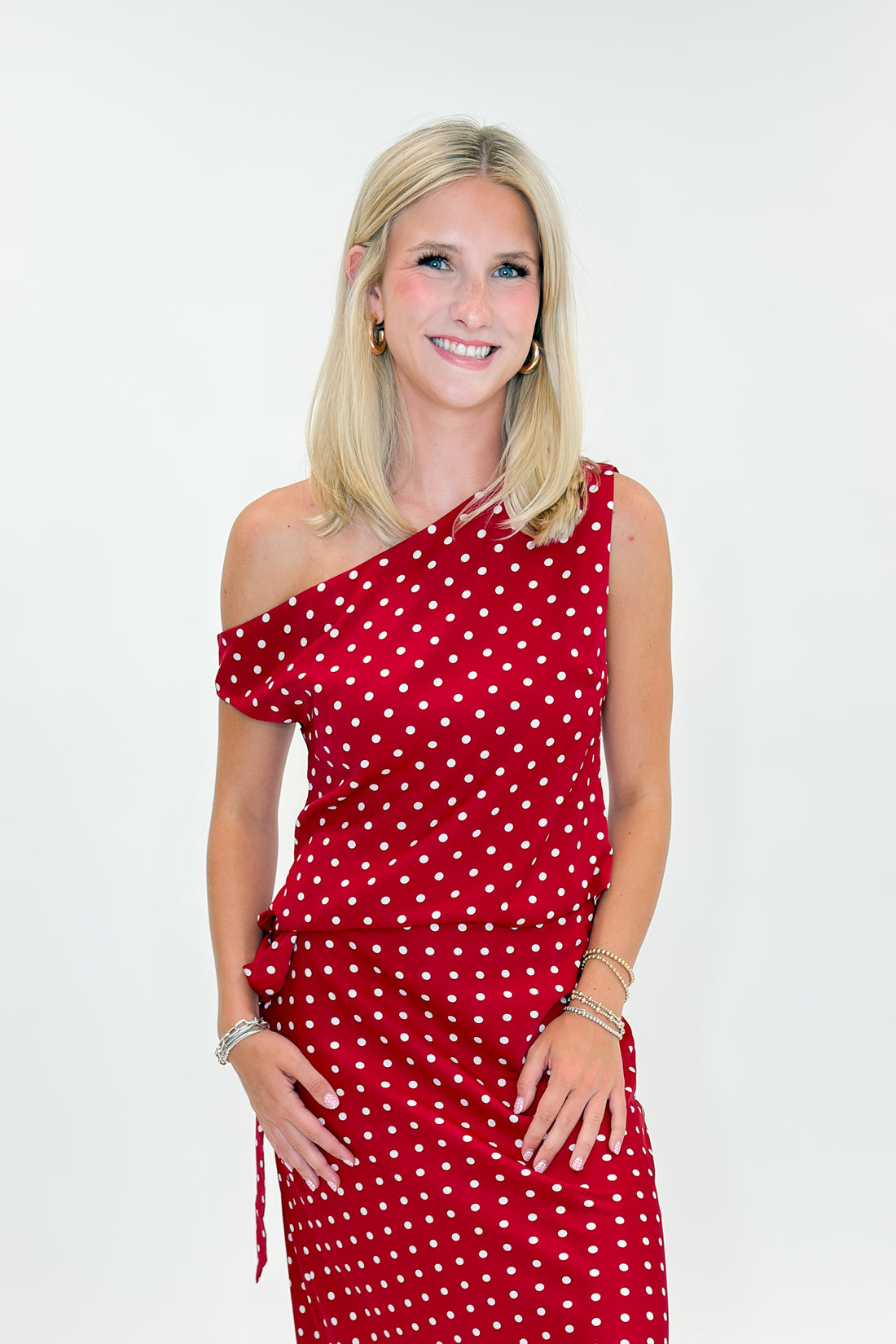 Front view of woman wearing Swagger Boutique’s Red &amp; White Polka Dot Midi Skirt with Red &amp; White Polka Dot Asymmetrical Tank against white studio background.