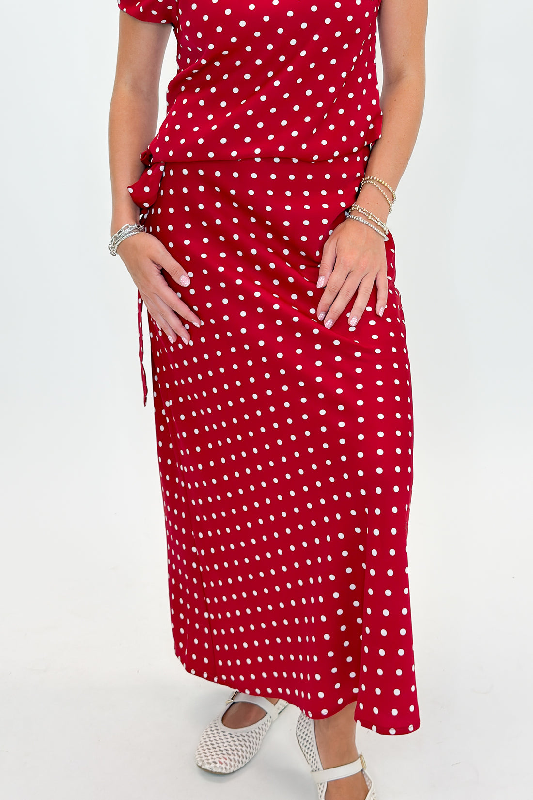 Front view of woman wearing Swagger Boutique’s Red &amp; White Polka Dot Midi Skirt with Red &amp; White Polka Dot Asymmetrical Tank against white studio background.
