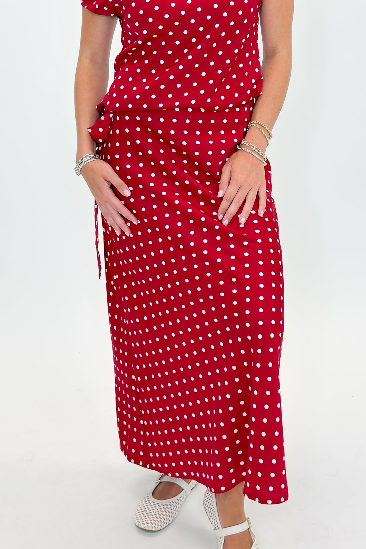 Front view of woman wearing Swagger Boutique’s Red &amp; White Polka Dot Midi Skirt with Red &amp; White Polka Dot Asymmetrical Tank against white studio background.