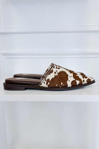 Regan- Cow Print Mule against white studio background side view.