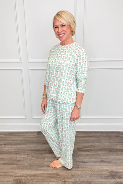 Side view of the Rosy Woodlands Annie Pajama Set, featuring a white background with green Christmas trees topped with pink bows. The relaxed long-sleeve top pairs with matching straight-leg pajama pants featuring convenient side pockets.