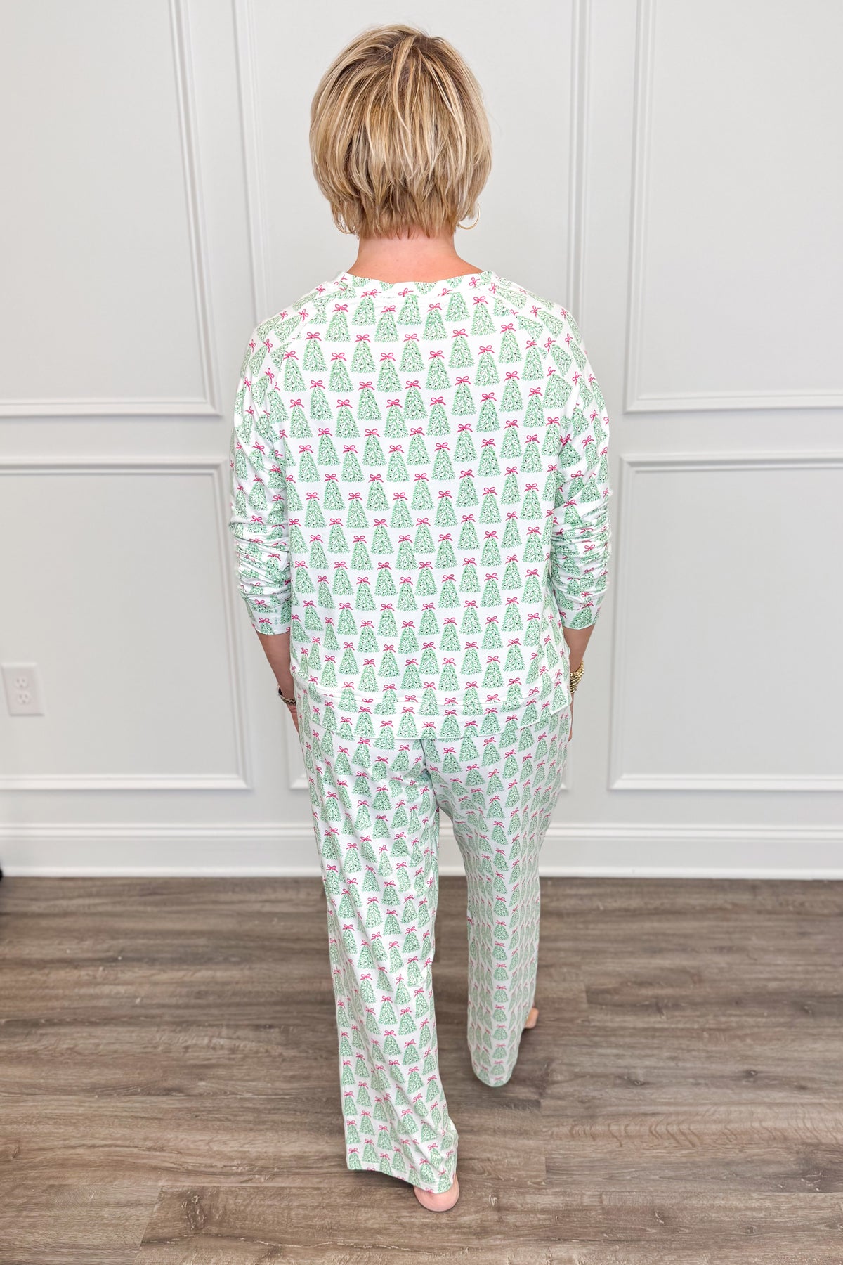 Back view of the Rosy Woodlands Annie Pajama Set, showcasing the festive green Christmas tree and pink bow print. The long-sleeve crewneck top features a comfortable, relaxed silhouette paired with matching full-length pajama pants.