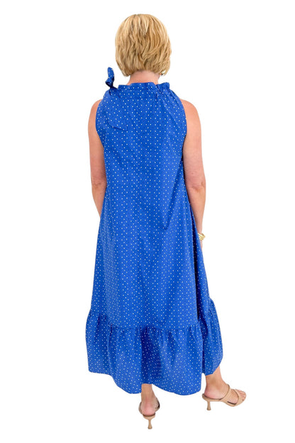 Back view of woman wearing Swagger Boutique’s Royal Blue Polka Dot Tue Neck Midi Dress against white studio background.