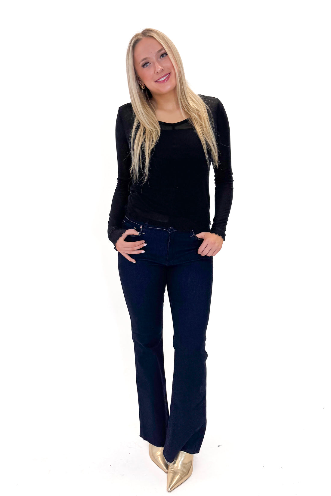 Front view of woman wearing Black Sheer Long Sleeve Top with jeans against white studio background.