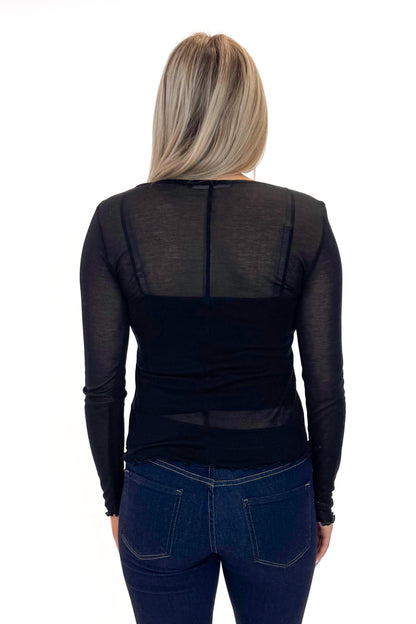 Back view of woman wearing Black Sheer Long Sleeve Top with jeans against white studio background.