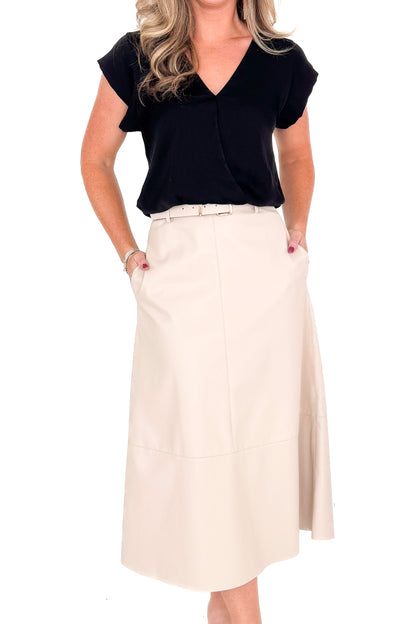 Front view of woman wearing Ecru Faux Leather Midi Skirt and black top against white studio background.