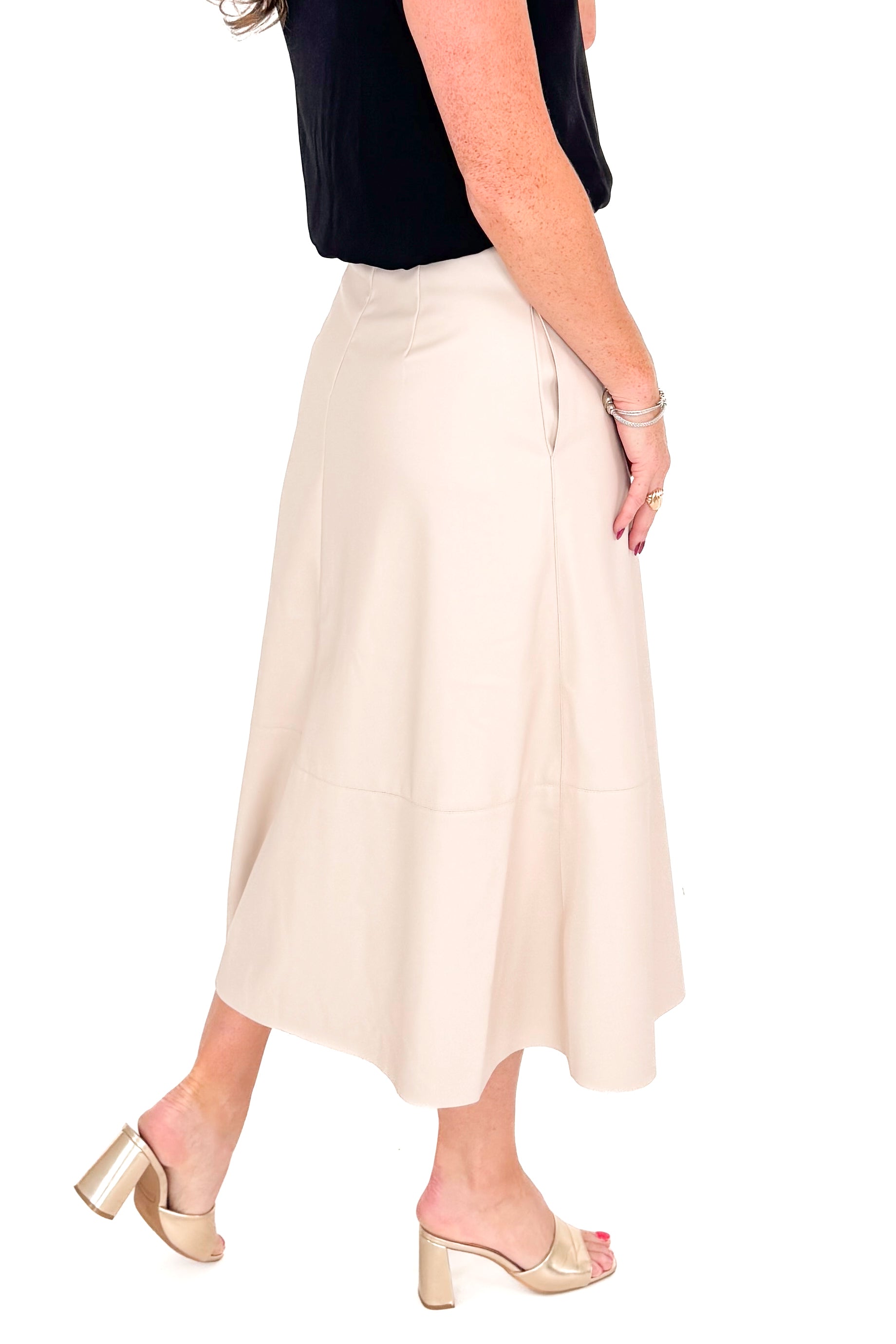 Side detailed view of woman wearing Ecru Faux Leather Midi Skirt and black top against white studio background.