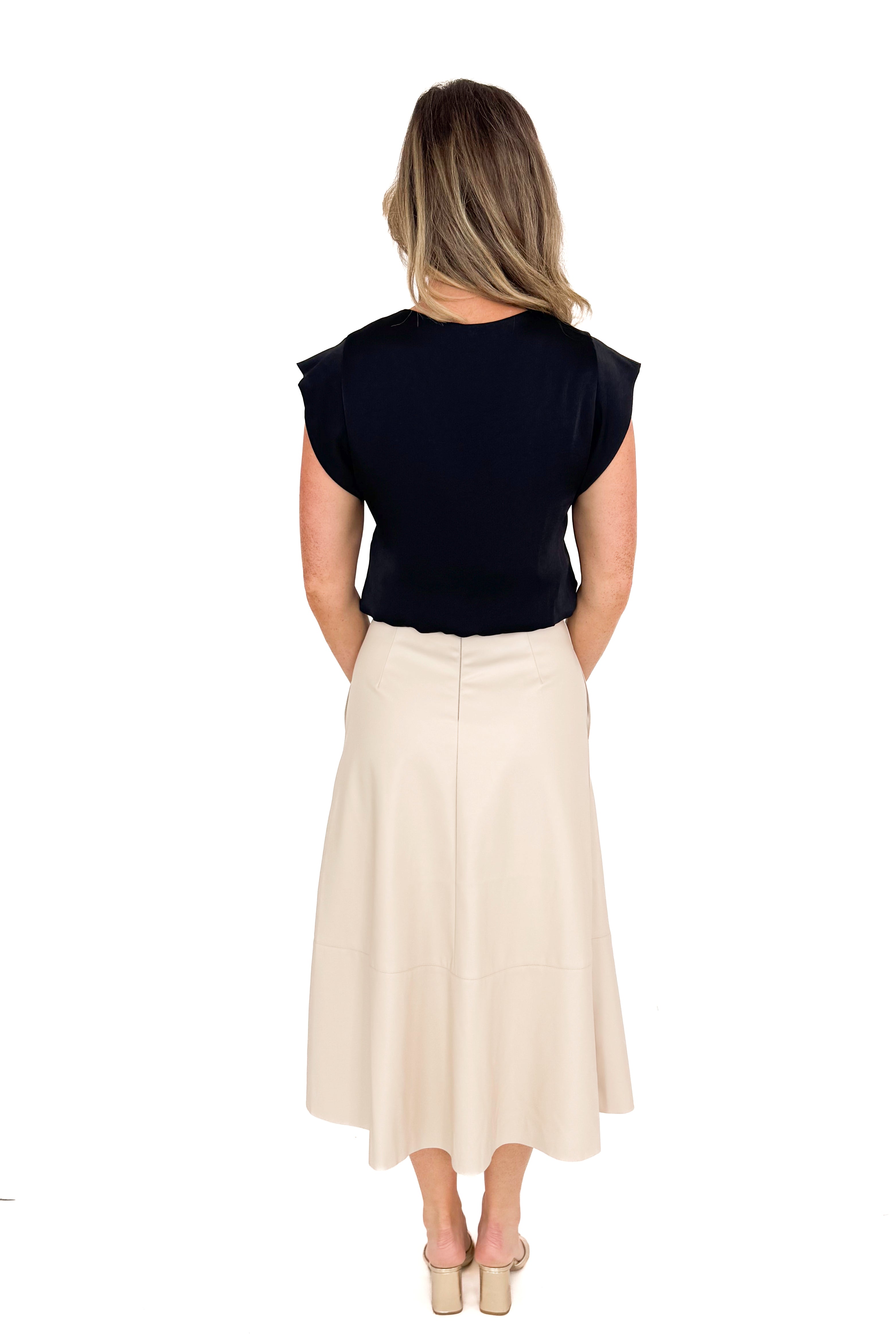 Back view of woman wearing Ecru Faux Leather Midi Skirt and black top against white studio background.