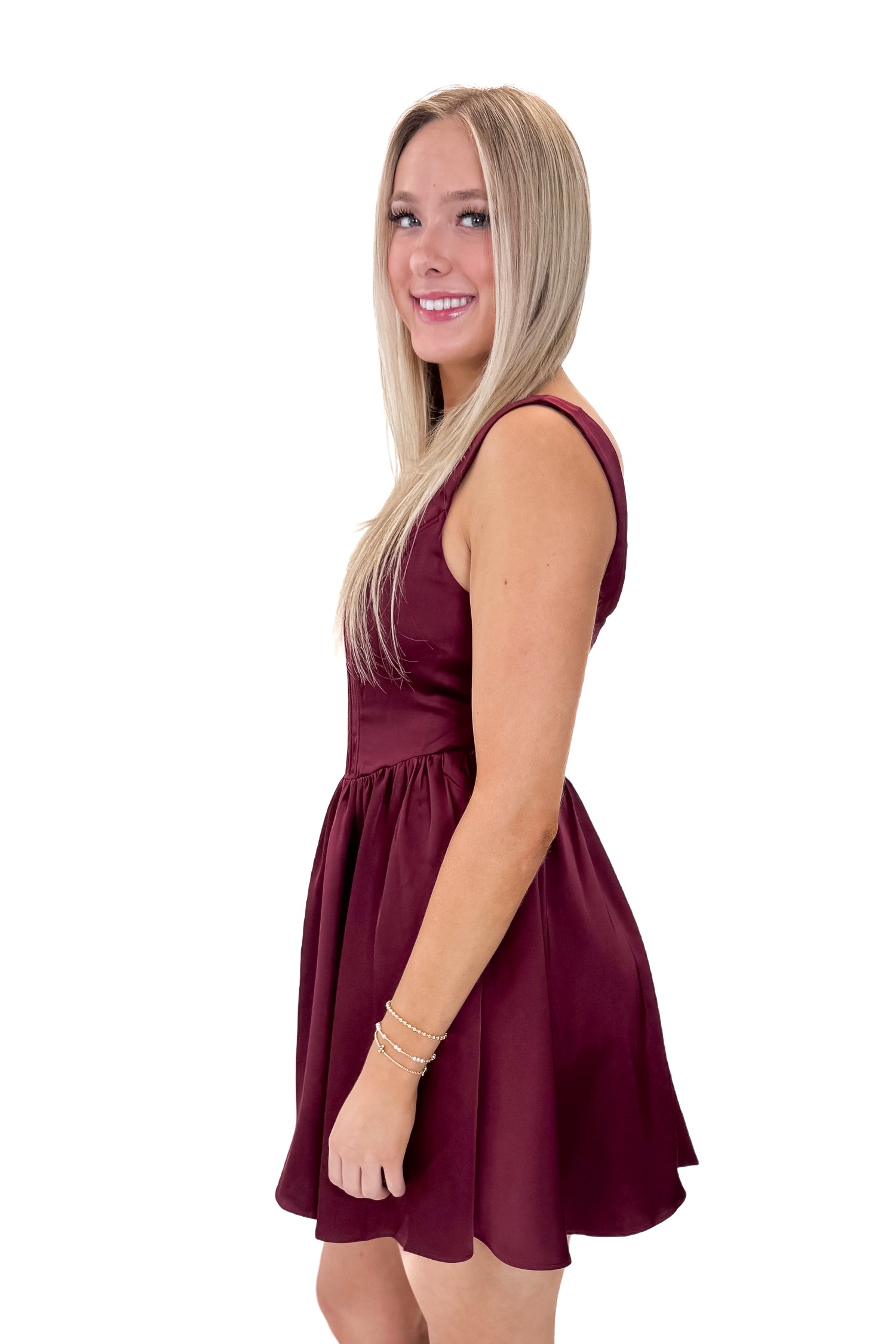 Side view of woman wearing Wine Corset Detail Satin Dress with heels against white studio background.