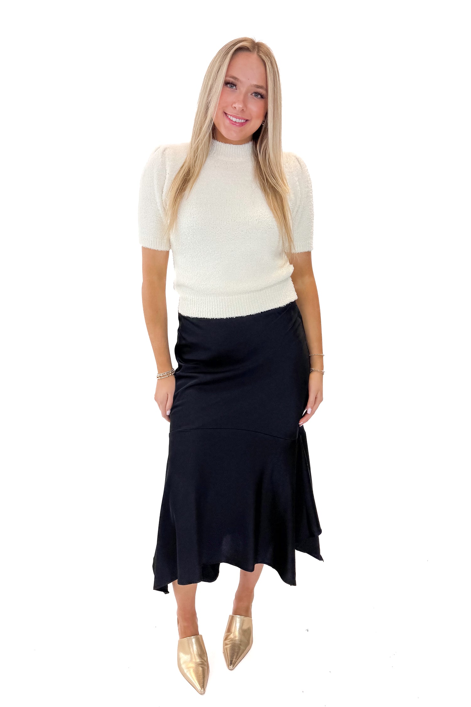 Front view of woman wearing Black Satin Handkerchief Hem Midi Skirt with sweater against white studio background.