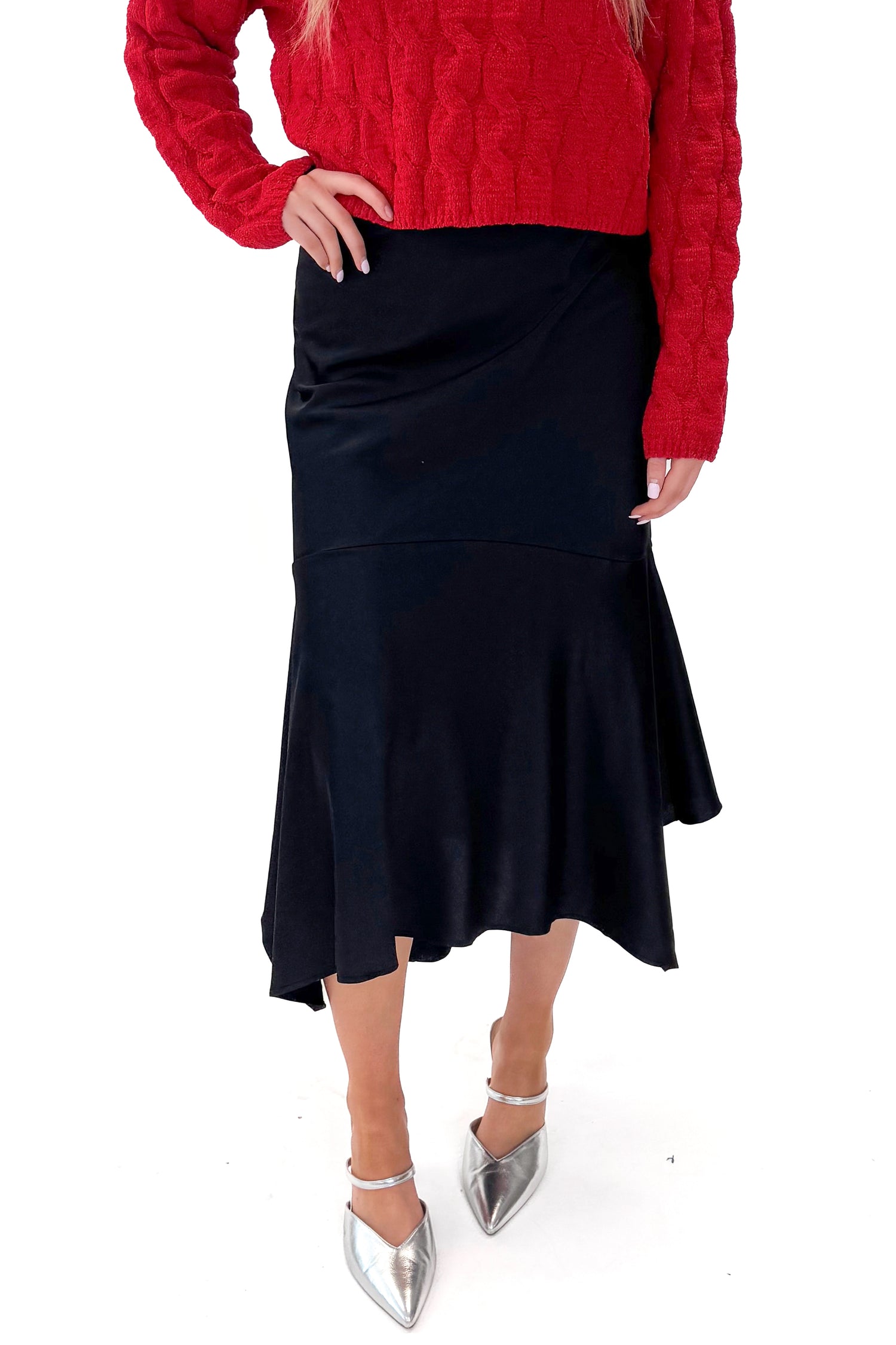 Front view of woman wearing Black Satin Handkerchief Hem Midi Skirt with sweater against white studio background.