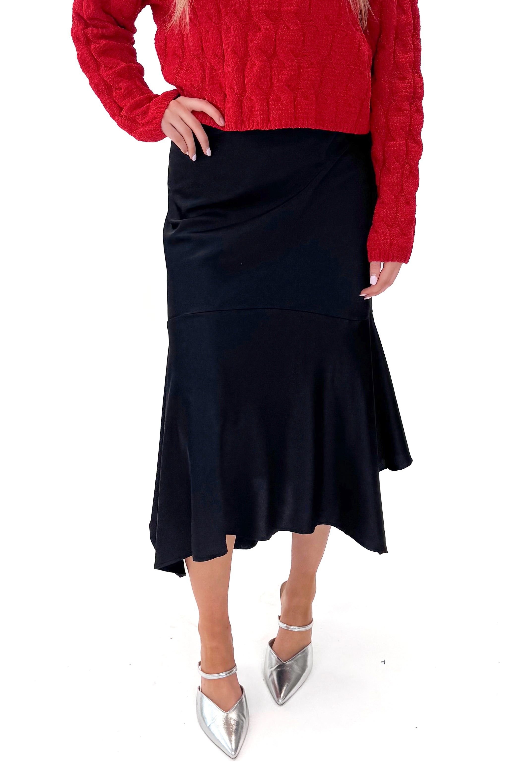 Front view of woman wearing Black Satin Handkerchief Hem Midi Skirt with sweater against white studio background.