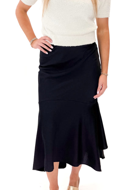 Front view of woman wearing Black Satin Handkerchief Hem Midi Skirt with sweater against white studio background.