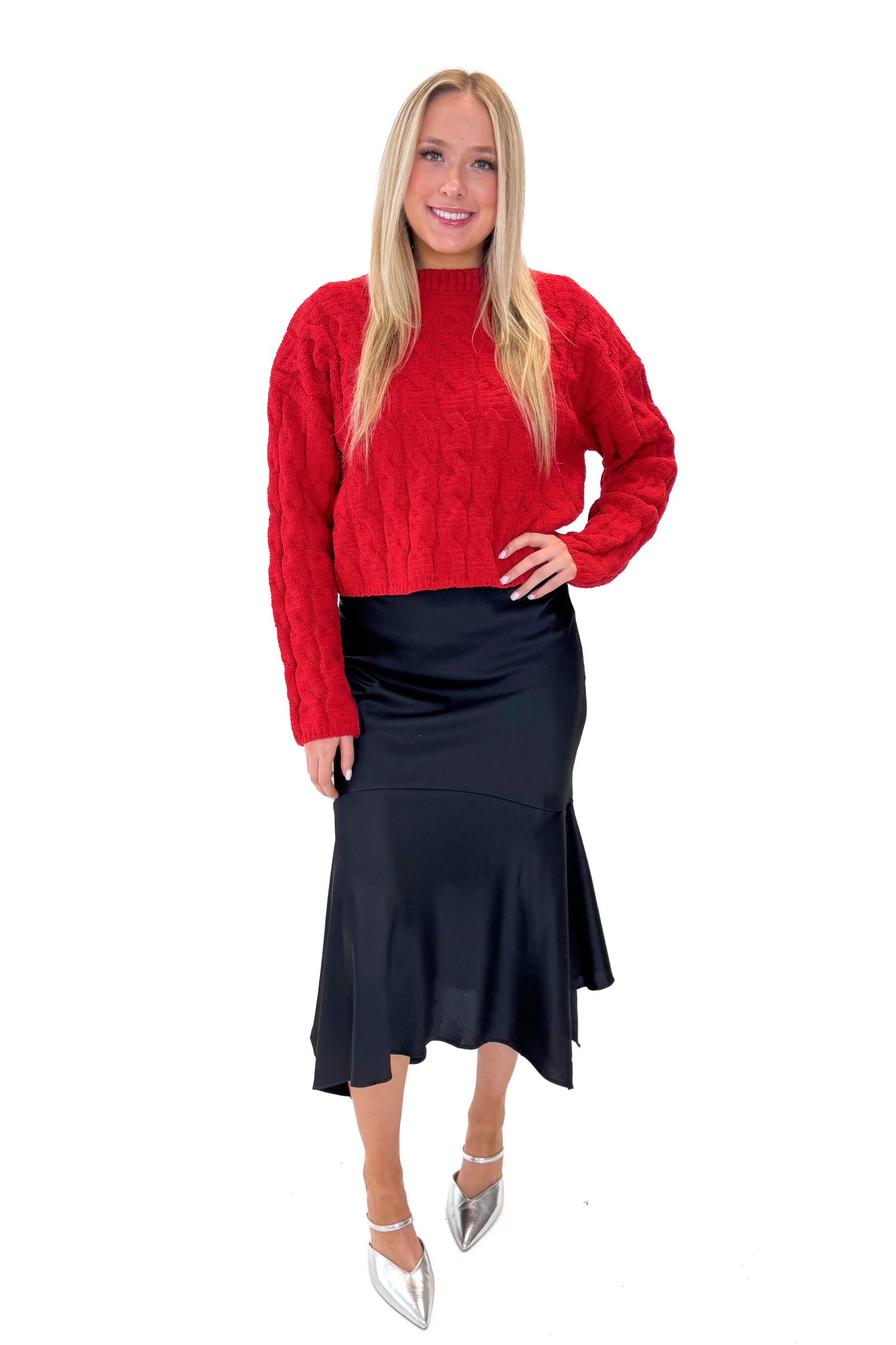 Front view of woman wearing Black Satin Handkerchief Hem Midi Skirt with sweater against white studio background.