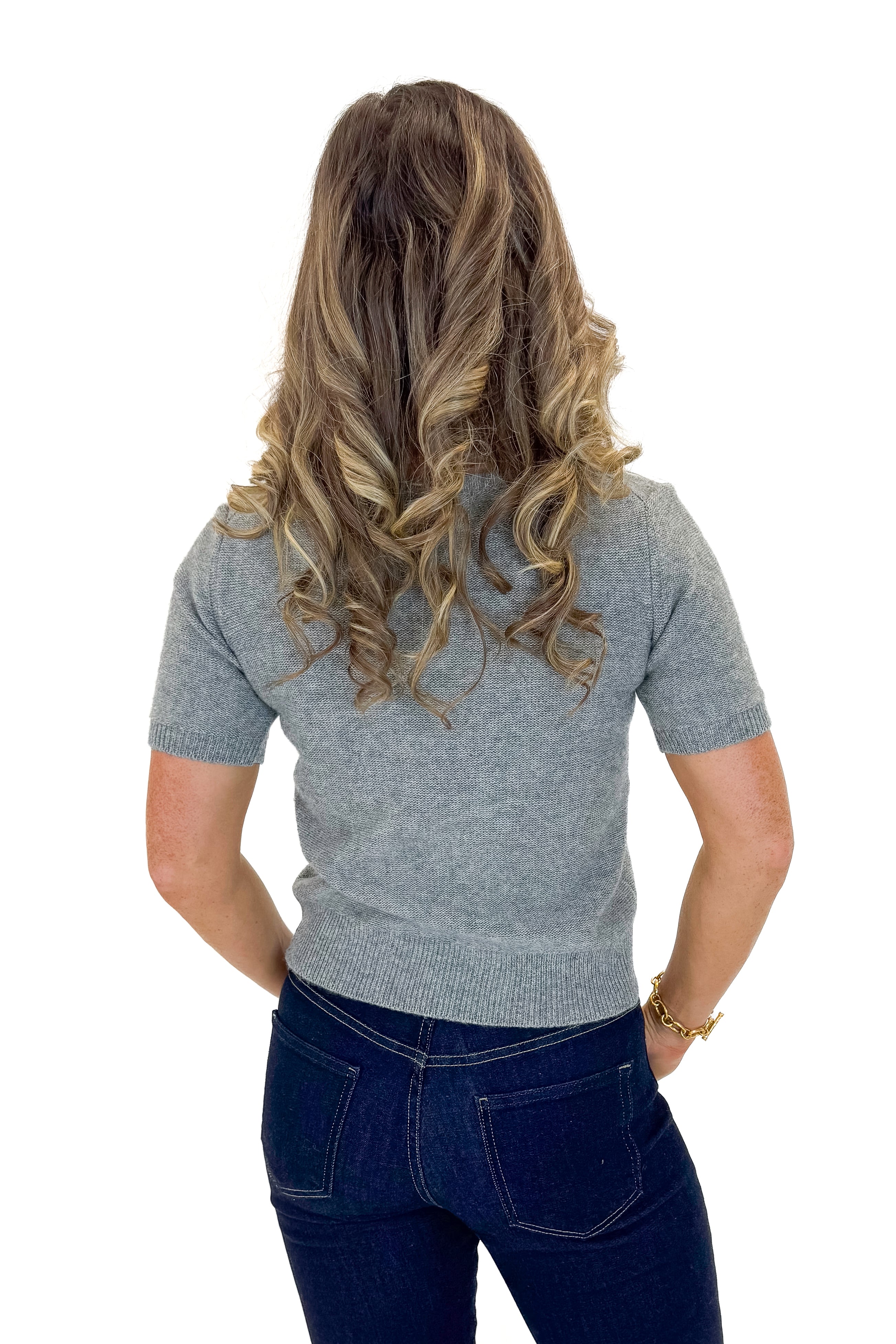 Back view of woman wearing Grey Short Sleeve Crewneck Sweater with jeans against white studio background.
