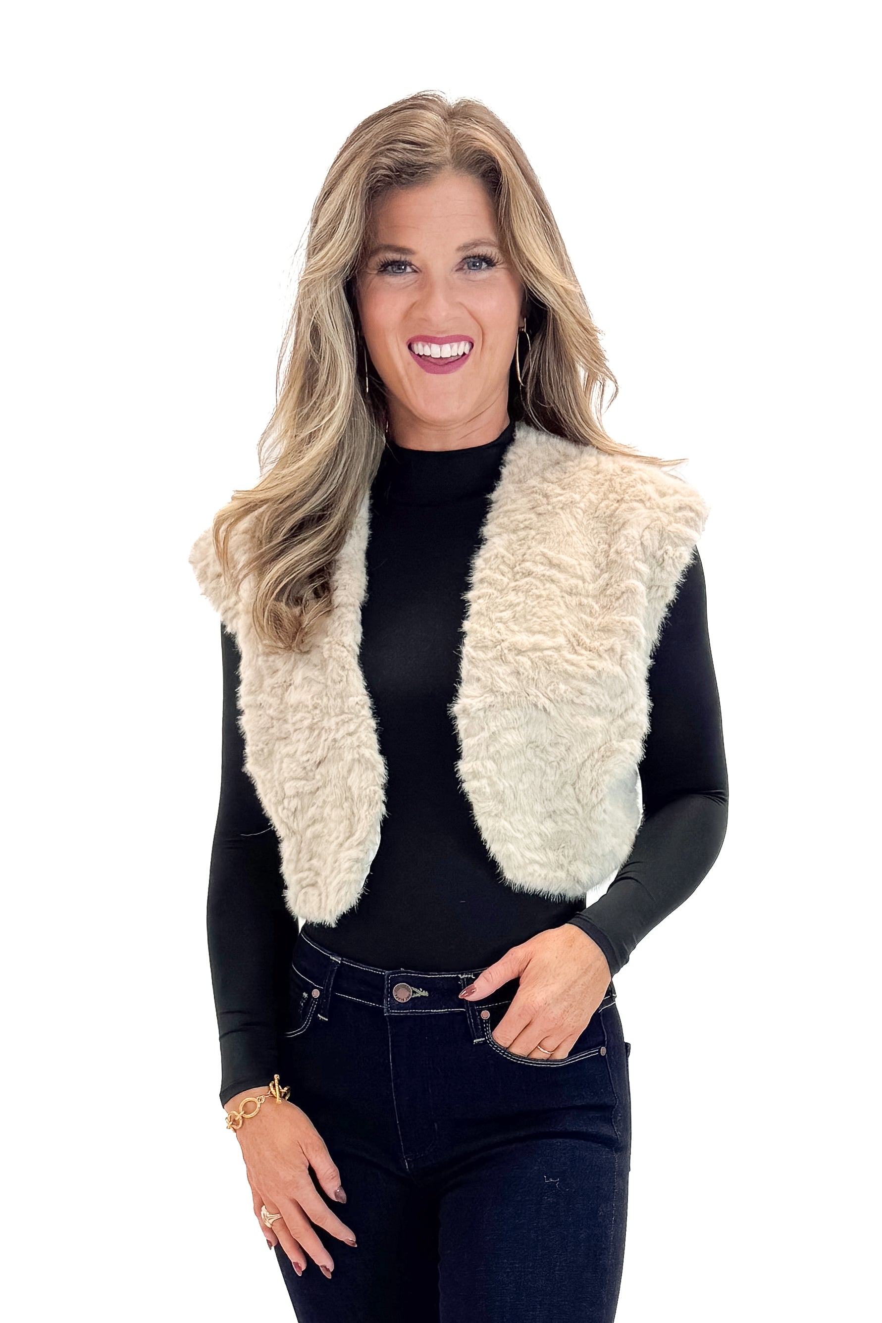 Front view of woman wearing Taupe Cropped Faux Fur Vest with jeans against white studio background.