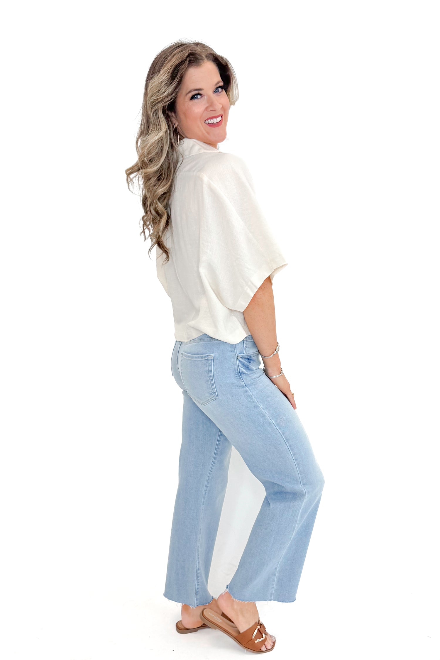 Side view of woman wearing Linen V-neck Collared Top with jeans against white studio background.