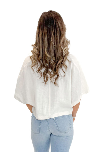 Back view of woman wearing Linen V-neck Collared Top with jeans against white studio background.