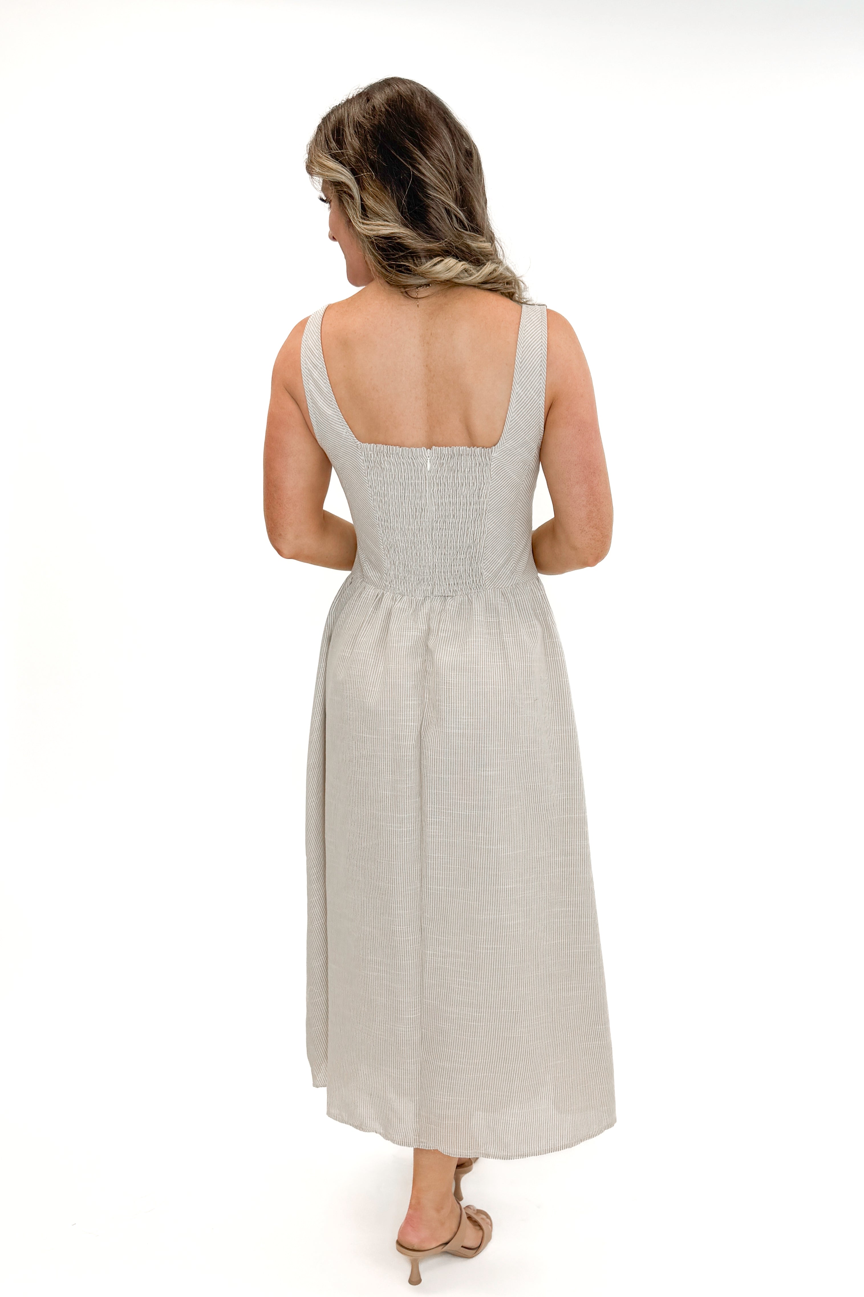 Back view of woman wearing Taupe Striped V-Waist Dress against white studio background.