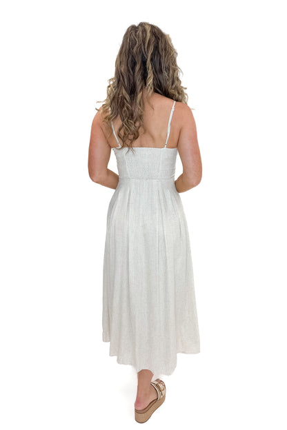 Back view of woman wearing Linen Pleat Detail Tank Dress with sandals against white studio background.