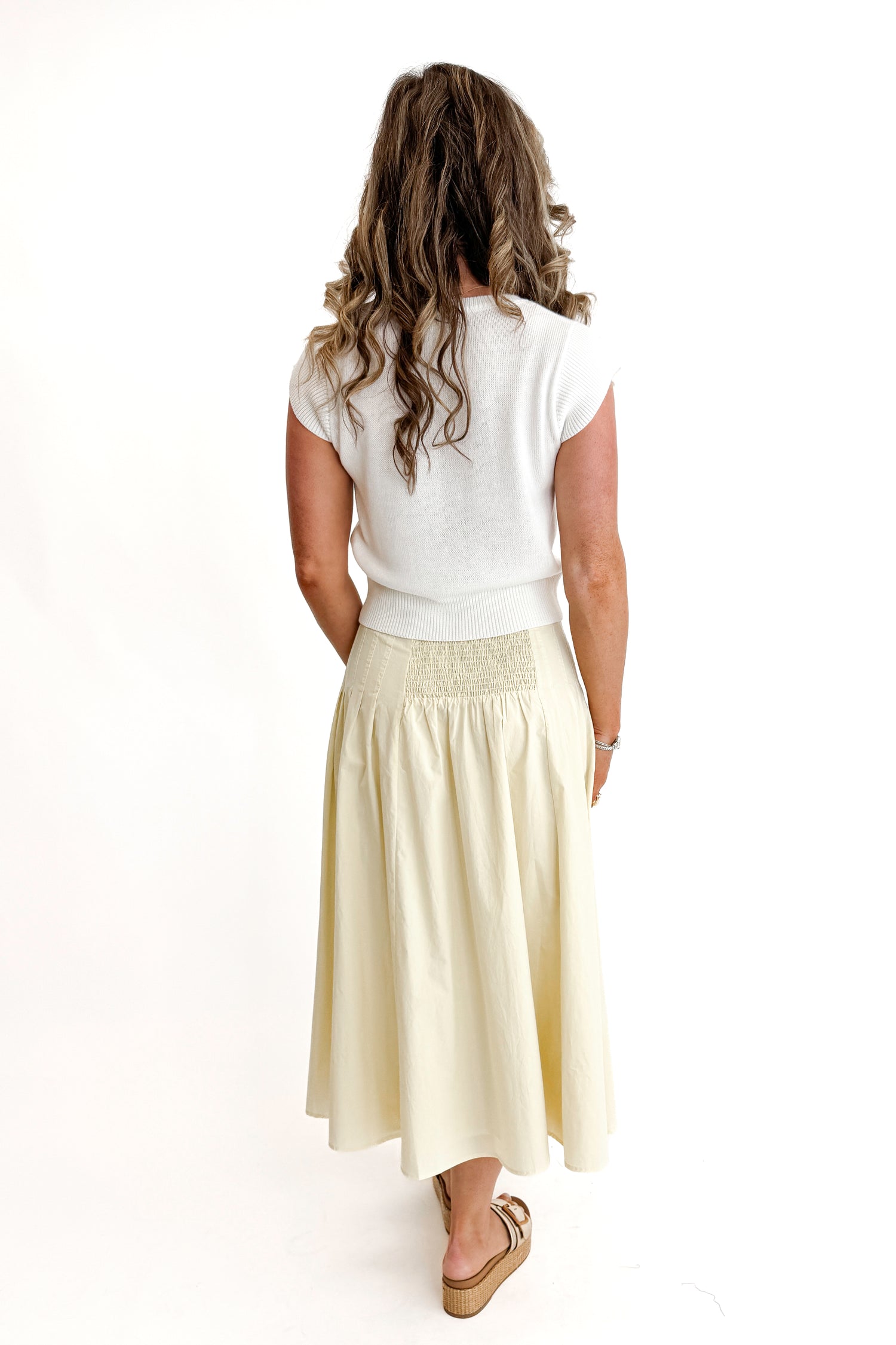 Back view of woman wearing top with Yellow Pleat Detail Midi Skirt against white studio background.