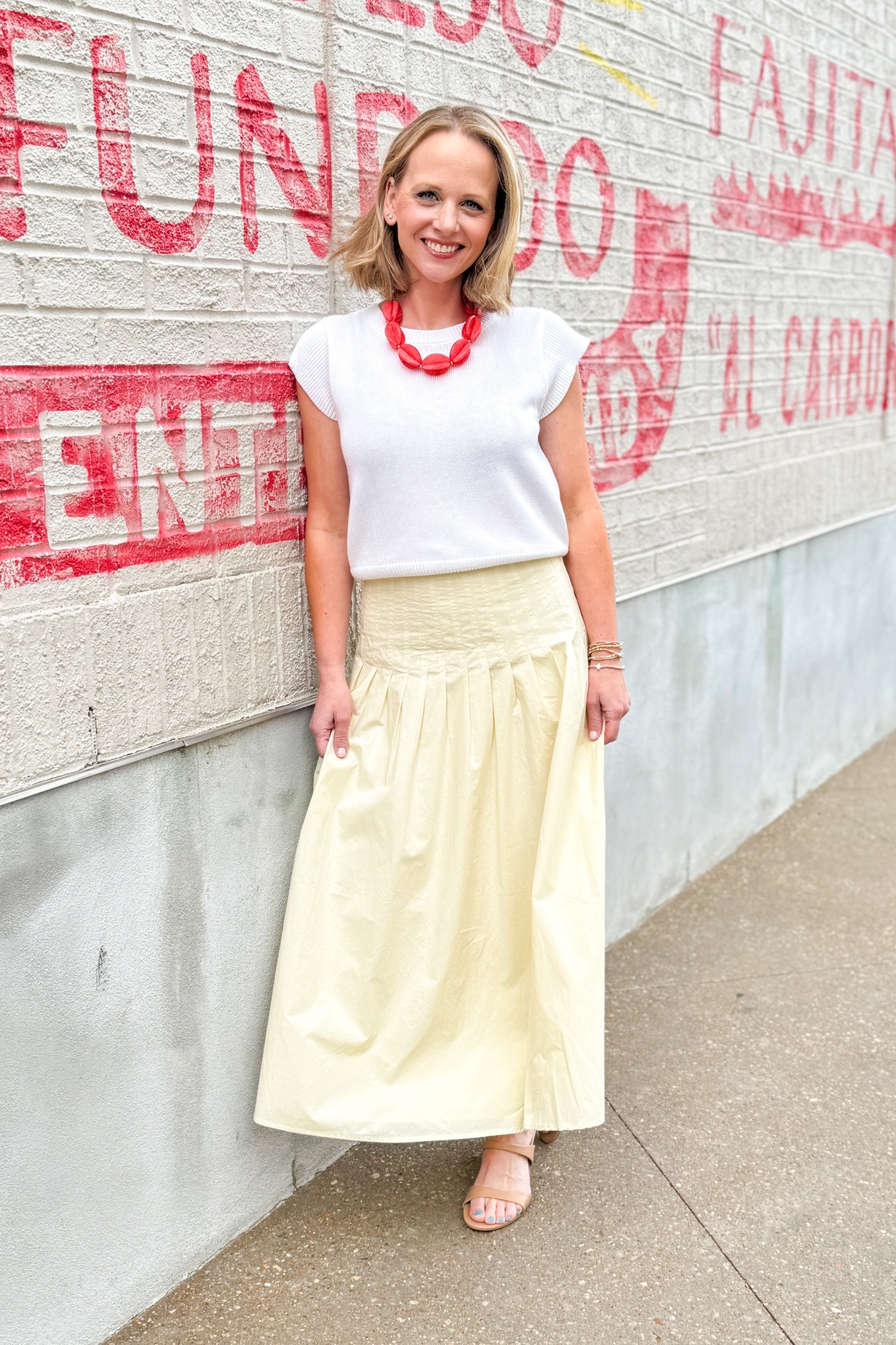 Front view of woman wearing top with Yellow Pleat Detail Midi Skirt standing outside.