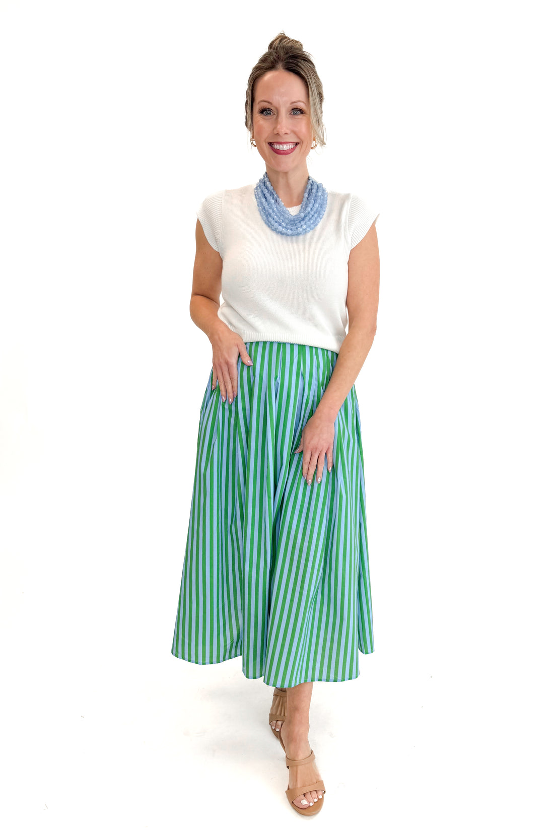 Front view of woman wearing Green &amp; Blue Striped Skirt by Entro with white sweater against white studio background.