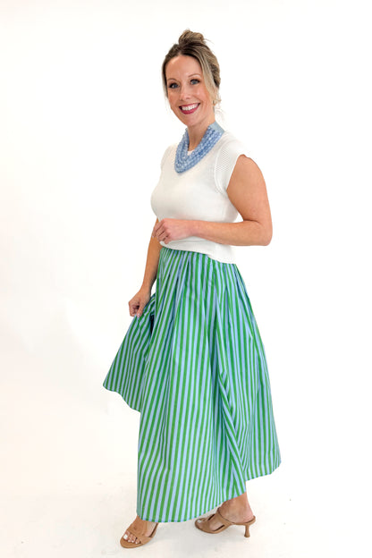 Side view of woman wearing Green &amp; Blue Striped Skirt by Entro with white sweater against white studio background.