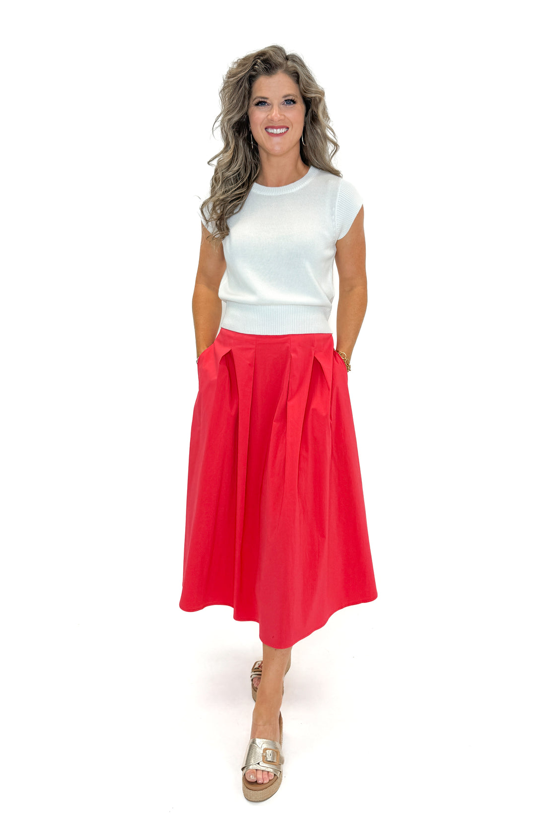 Front view of woman wearing Red Pleat Detail Midi Skirt by Entro with top against white studio background.