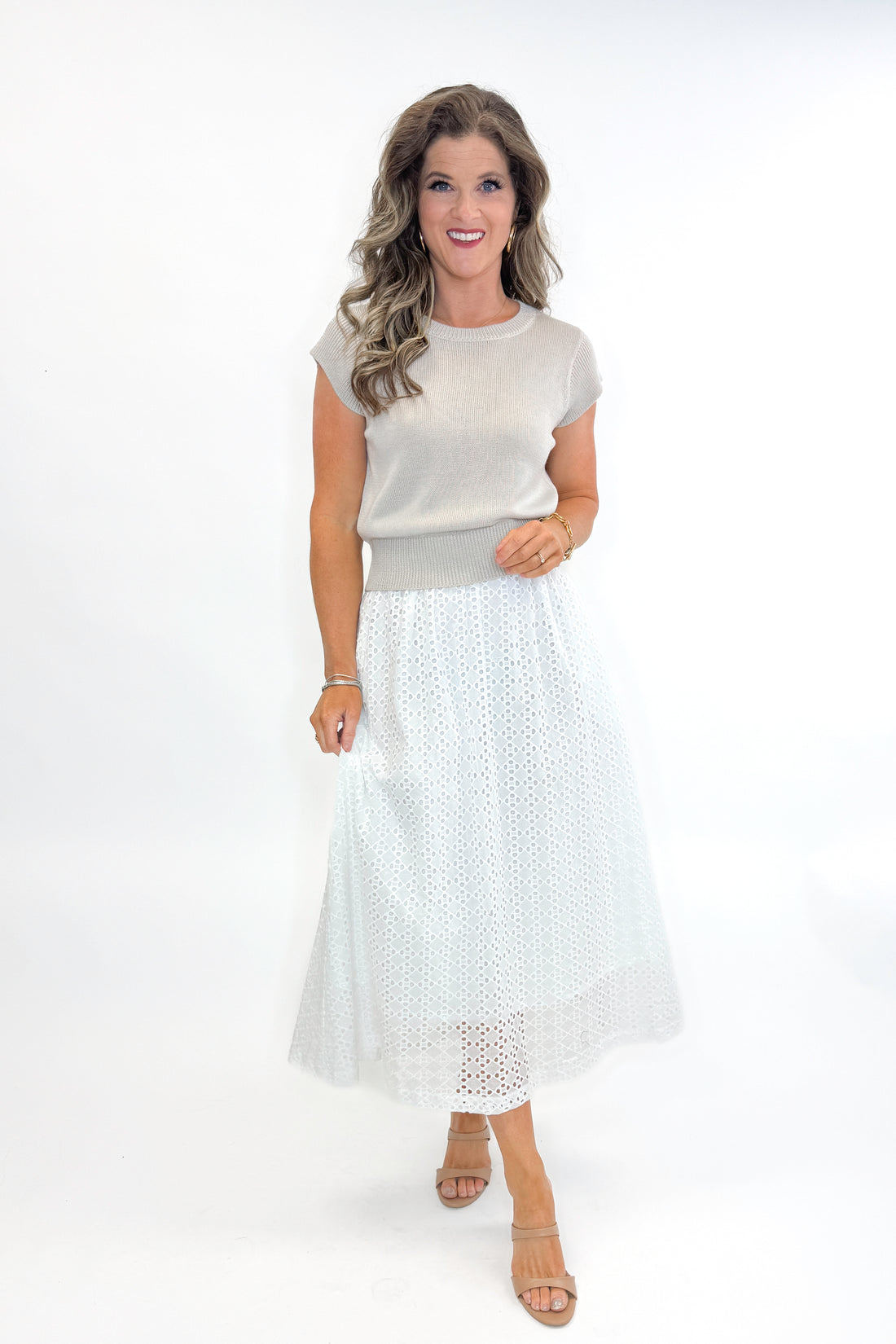 Front view of woman wearing Off White Eyelet Midi Skirt by Entro with sweater against white studio background.