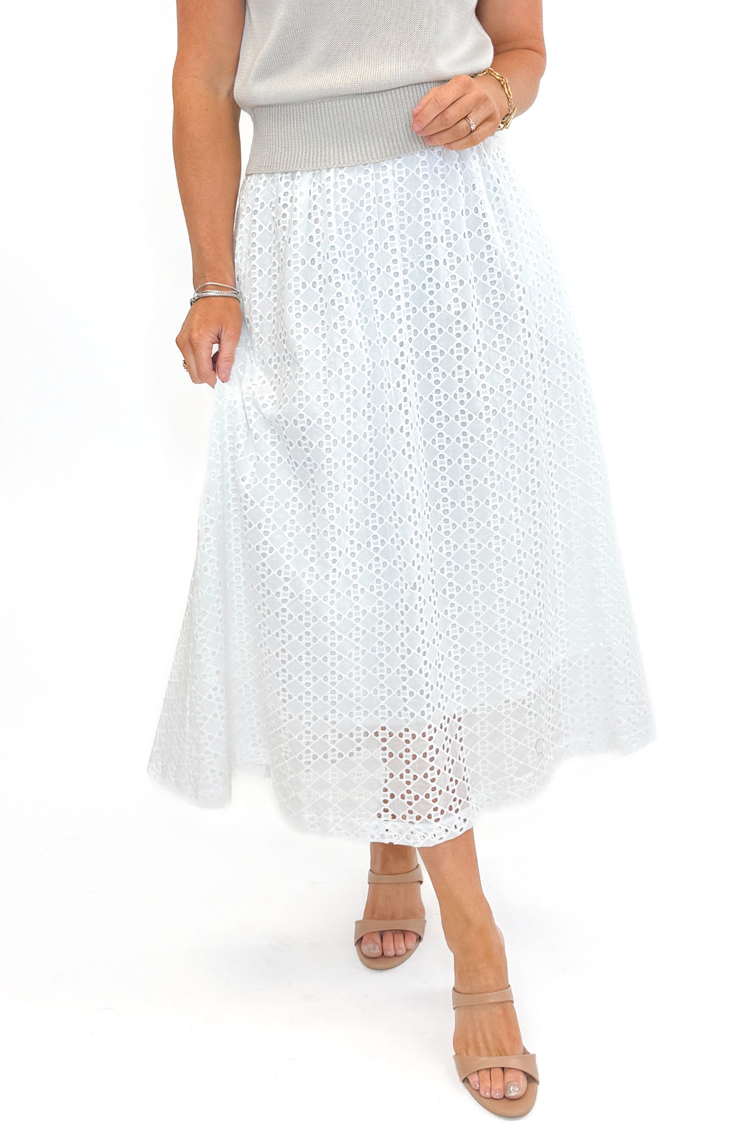 Front view of woman wearing Off White Eyelet Midi Skirt by Entro with sweater against white studio background.