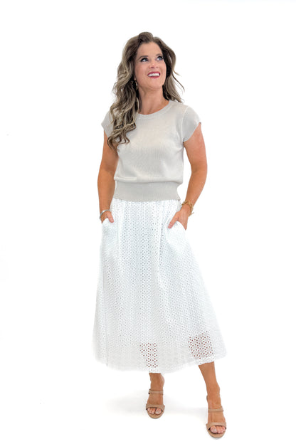 Front view of woman wearing Off White Eyelet Midi Skirt by Entro with sweater against white studio background.