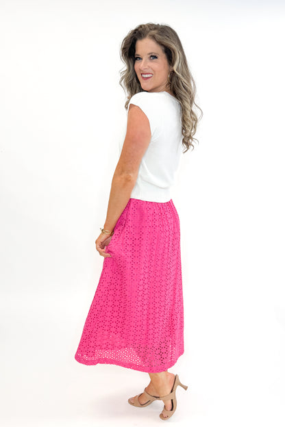 Side view of woman wearing white sweater with Hot Pink Eyelet Midi Skirt by Entro against white studio background.