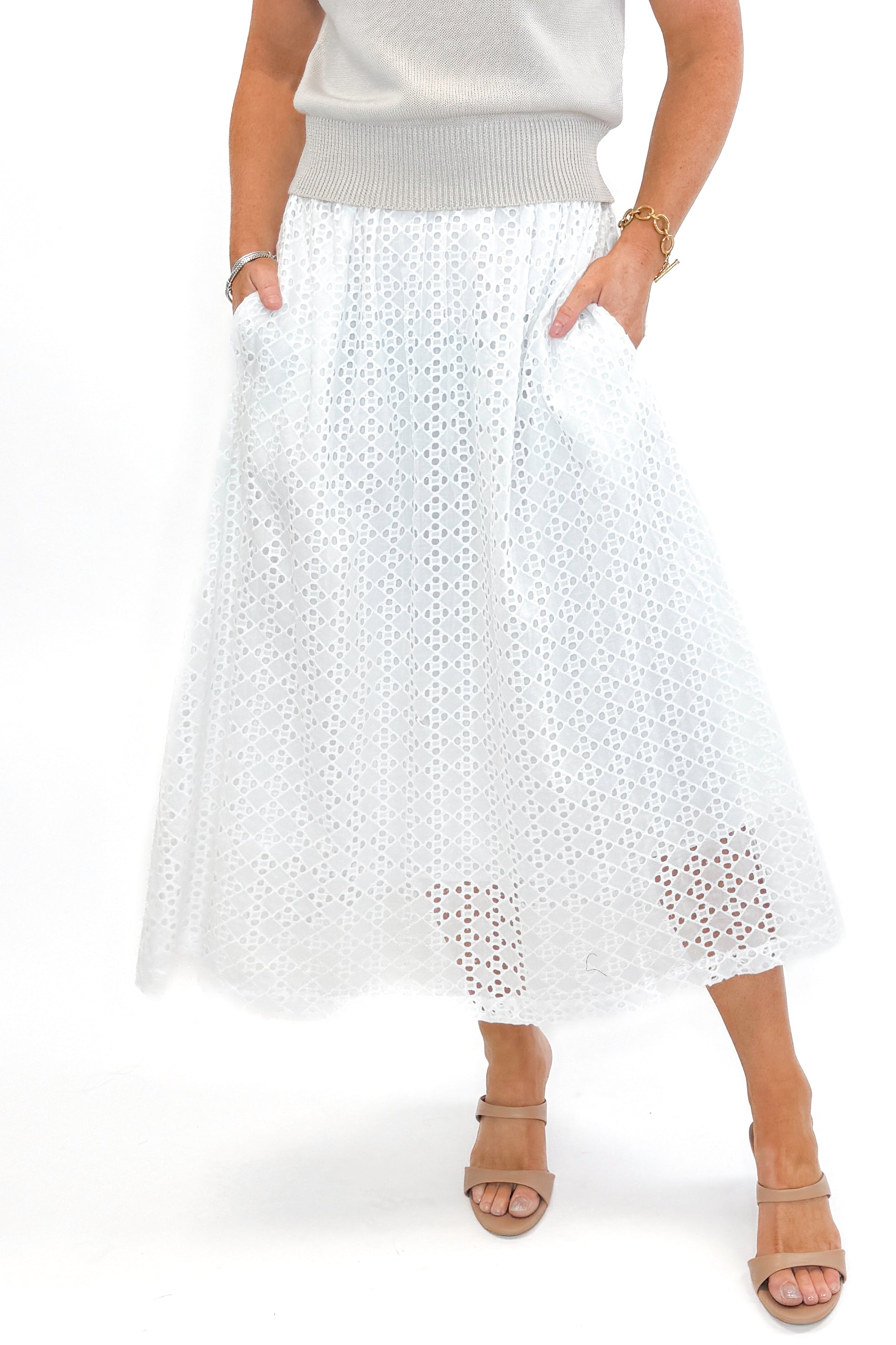 Front view of woman wearing Off White Eyelet Midi Skirt by Entro with sweater against white studio background.