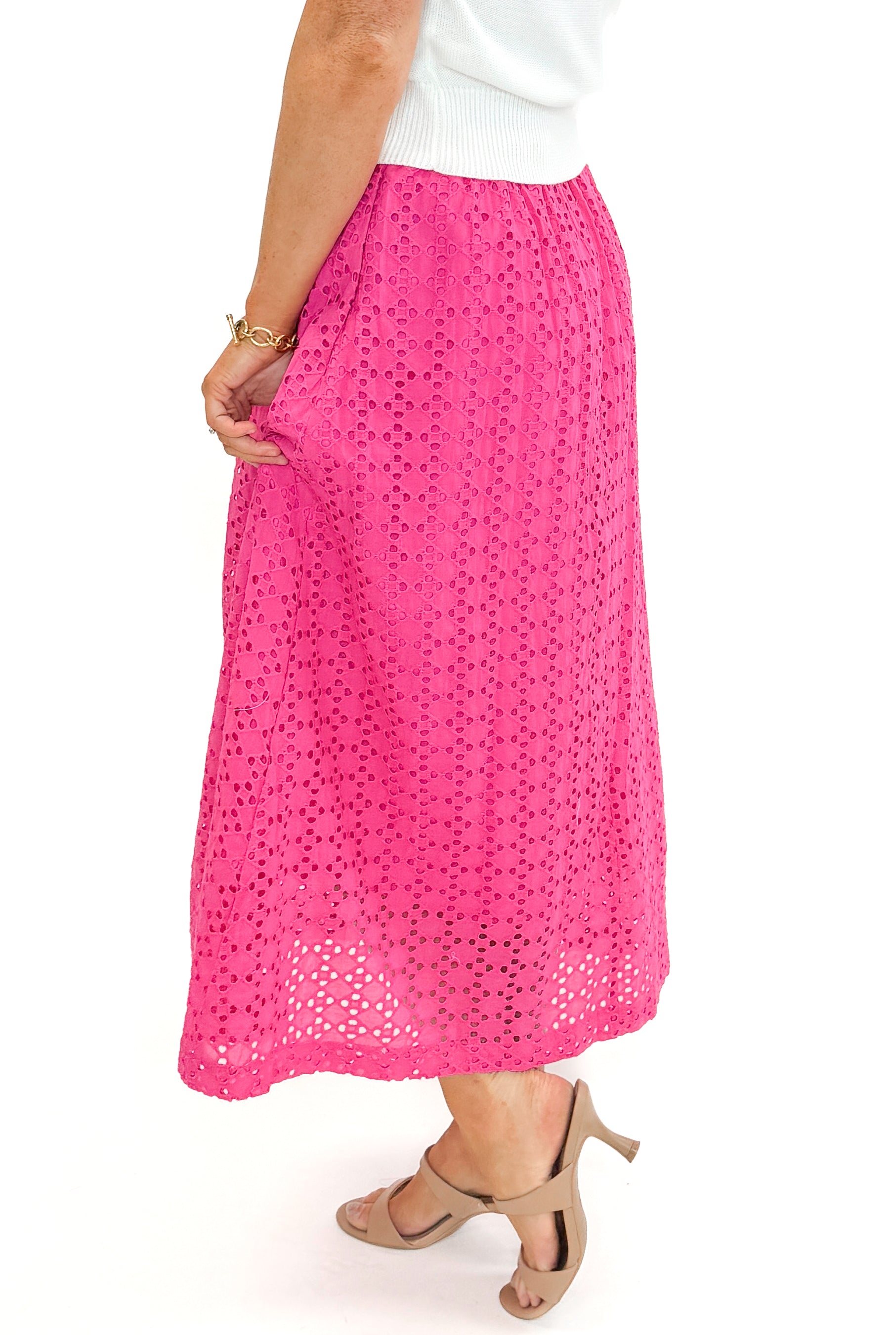 Side detail view of woman wearing white sweater with Hot Pink Eyelet Midi Skirt by Entro against white studio background.