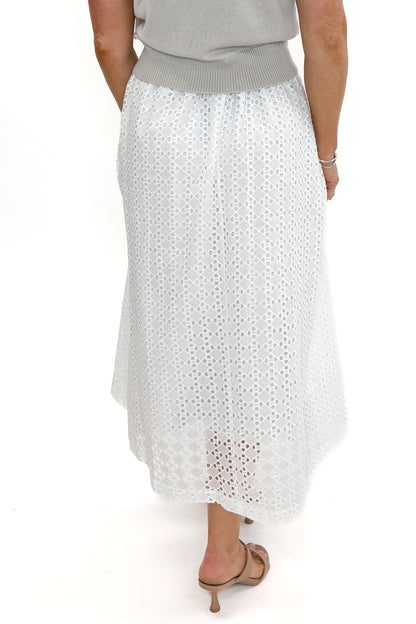 Back view of woman wearing Off White Eyelet Midi Skirt by Entro with sweater against white studio background.